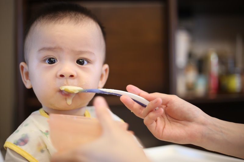 Ein Baby wird mit einem Löffel gefüttert. Es bekommt Babybrei als Nahrung.