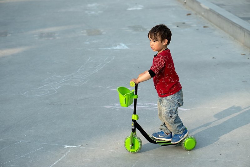 Ein Kind steht auf einem Roller.