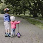 Zwei Kinder fahren mit einem Kinderroller
