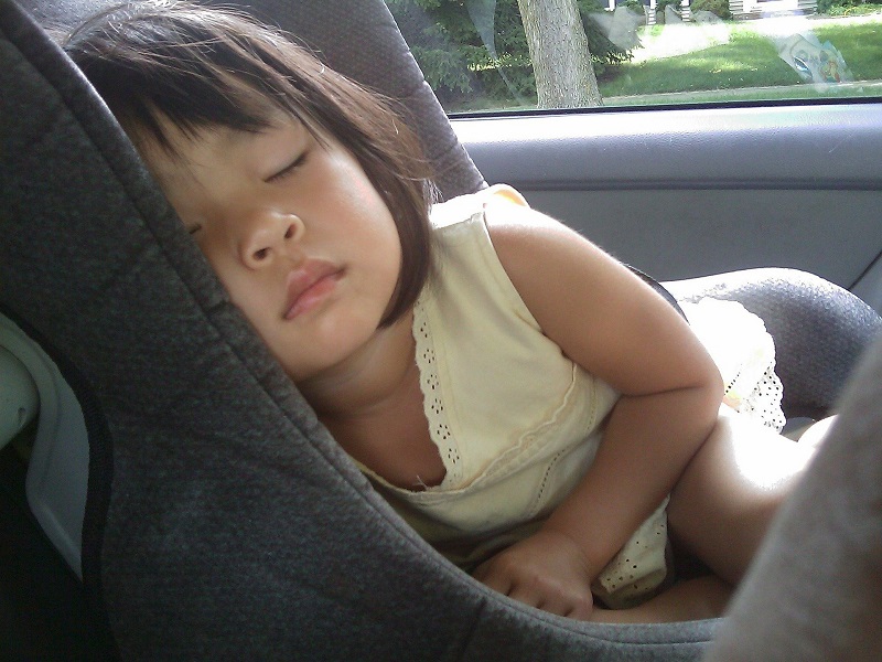 Ein Kind dass in einem Autokindersitz schläft.