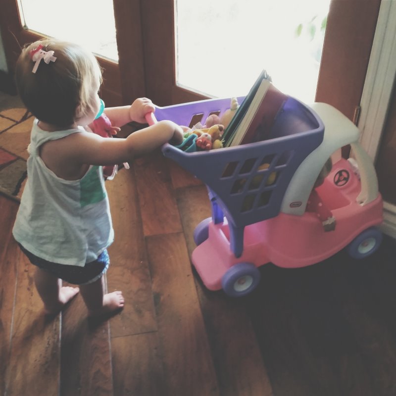 Kleinkind spielt mit einem Einkaufswagen.