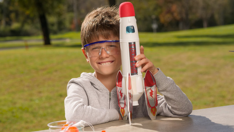 Kind mit Sicherheitsbrille und Rakete aus dem Experimentierkasten