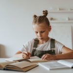 Mädchen schreibt an einem Kinderschreibtisch
