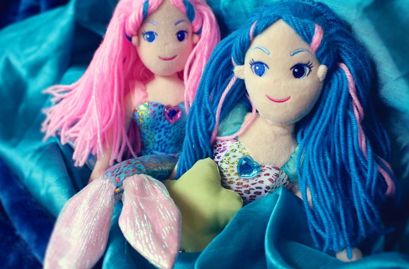 Spielzeug-Meerjungfrauen sitzen auf blauen Tüchern