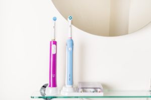 Zwei elektrische Zahnbürsten für Kinder auf einem Regal im Badezimmer.