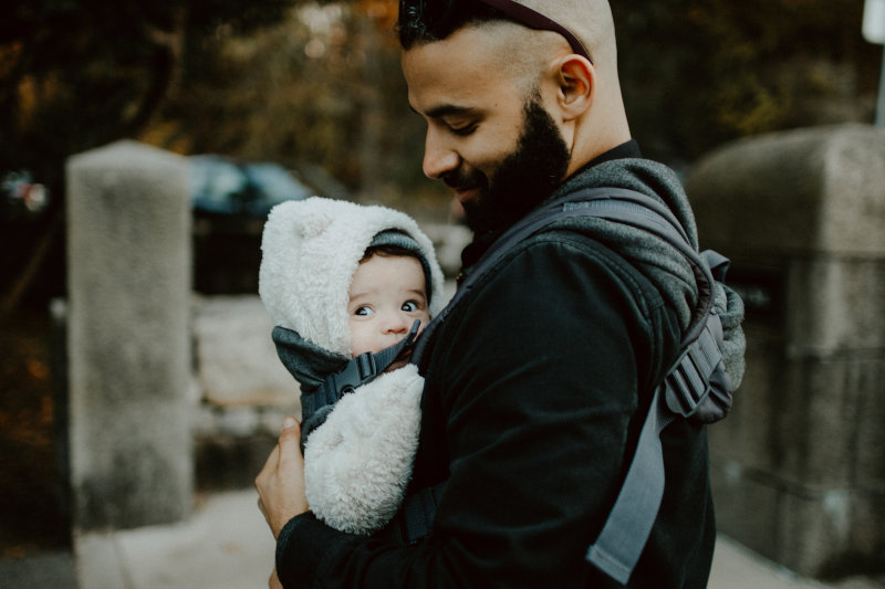 Vater trägt Kind in Babytrage
