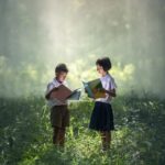 zwei Kinder lesen Literatur im Wald