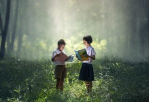 zwei Kinder lesen Literatur im Wald